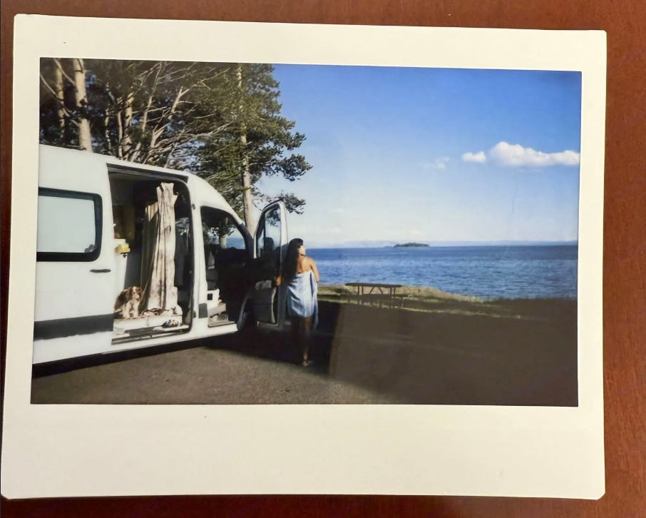 A scenic stop: Woman, dog, and open **RV rental** van by a lake. Perfect for a serene road trip adventure.