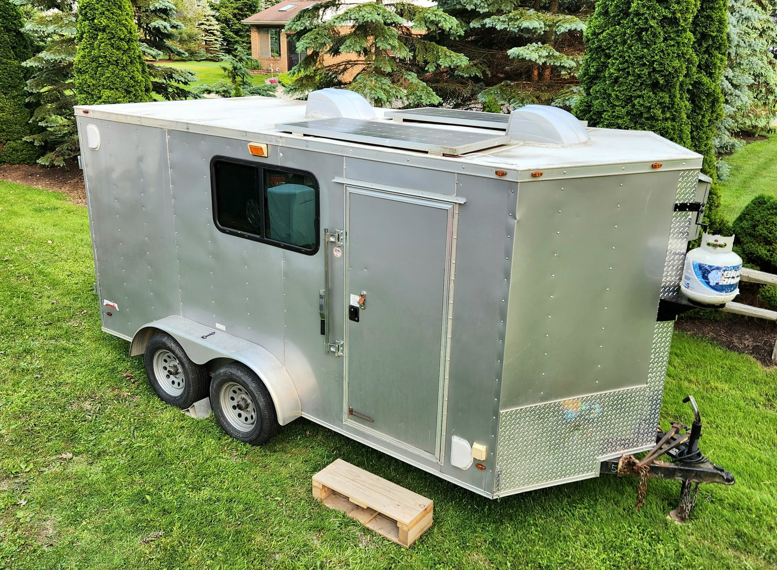 parked on grass.|A light gray enclosed cargo trailer with dual axles and rear doors
