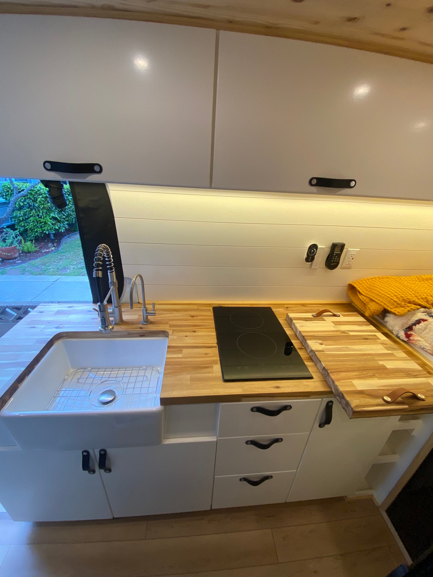 Modern **RV rental** kitchen: white cabinets, butcher block counters, farmhouse sink, and induction