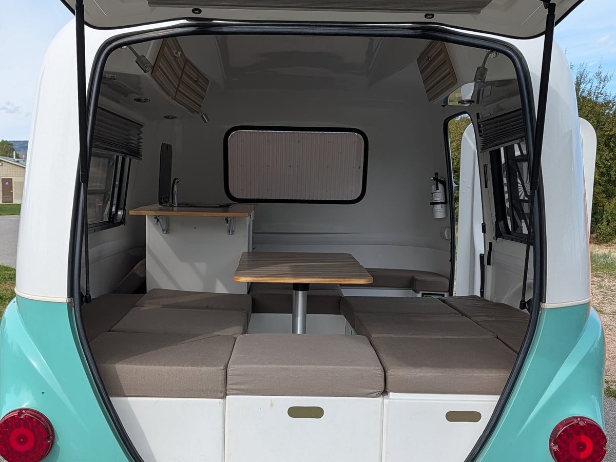 parked by a scenic lake with mountains in the background.|This vintage-style white and teal teardrop RV rental is ready for adventure in a scenic park — photo 3