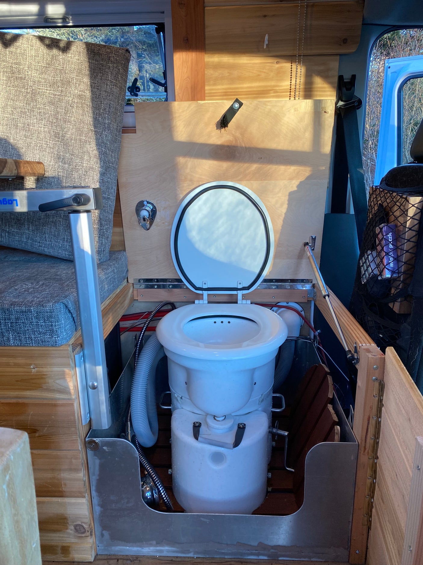 RV rental: Modern camper van interior featuring an open composting toilet and custom wood finishes.