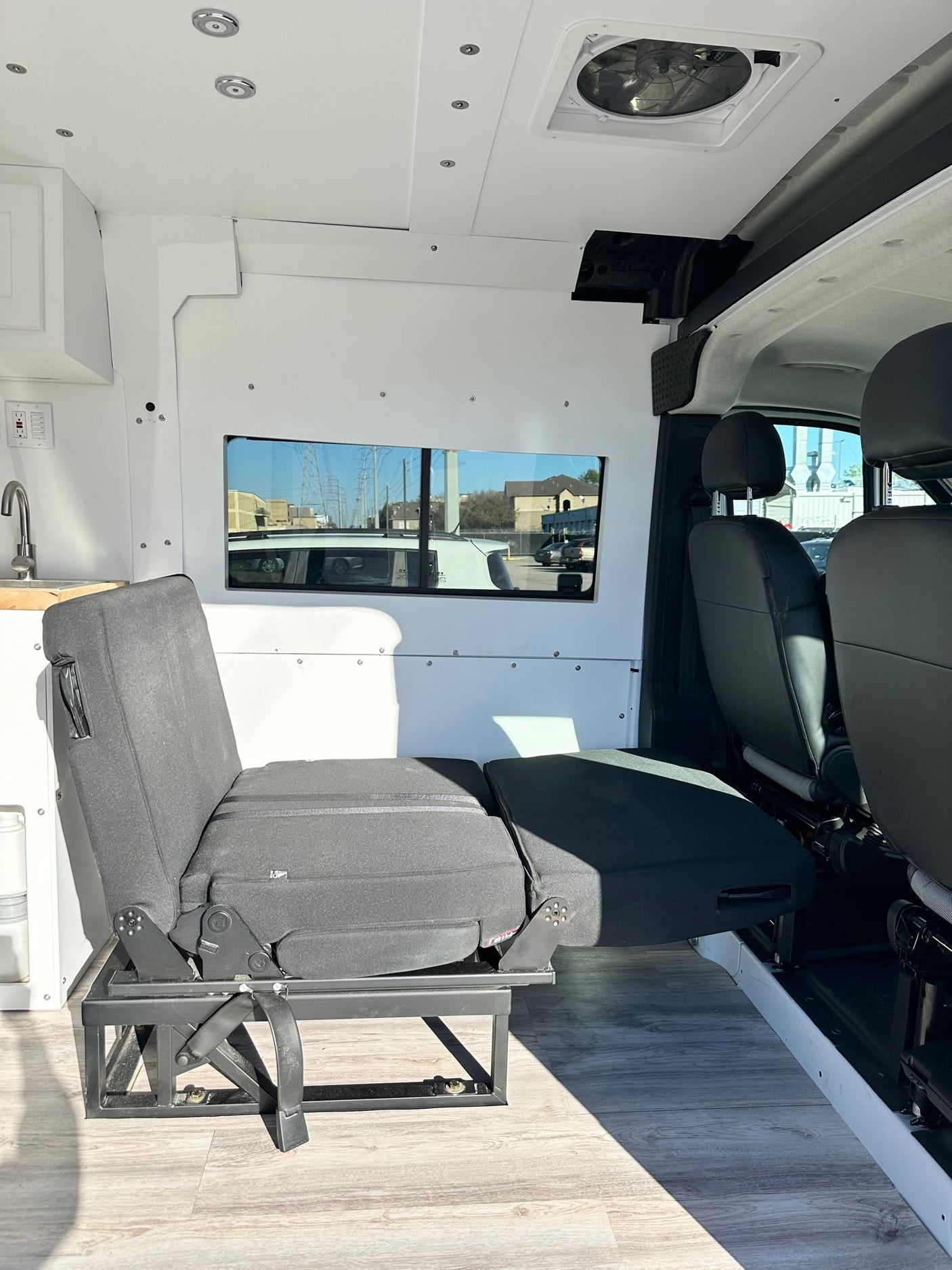 RV rental interior featuring a versatile bench seat/bed, mini-kitchen, and overhead fan. Ready for adventure!