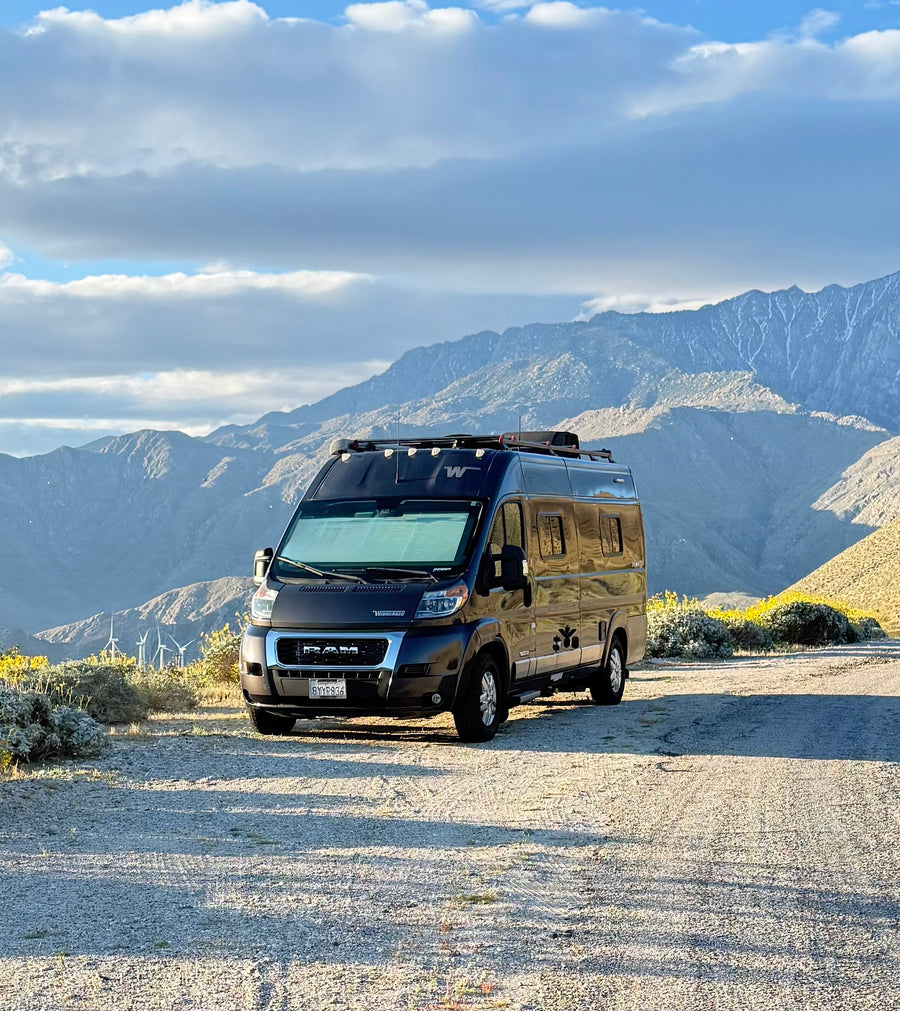 Scenic rv rental adventure: A black camper van is parked on a dirt road