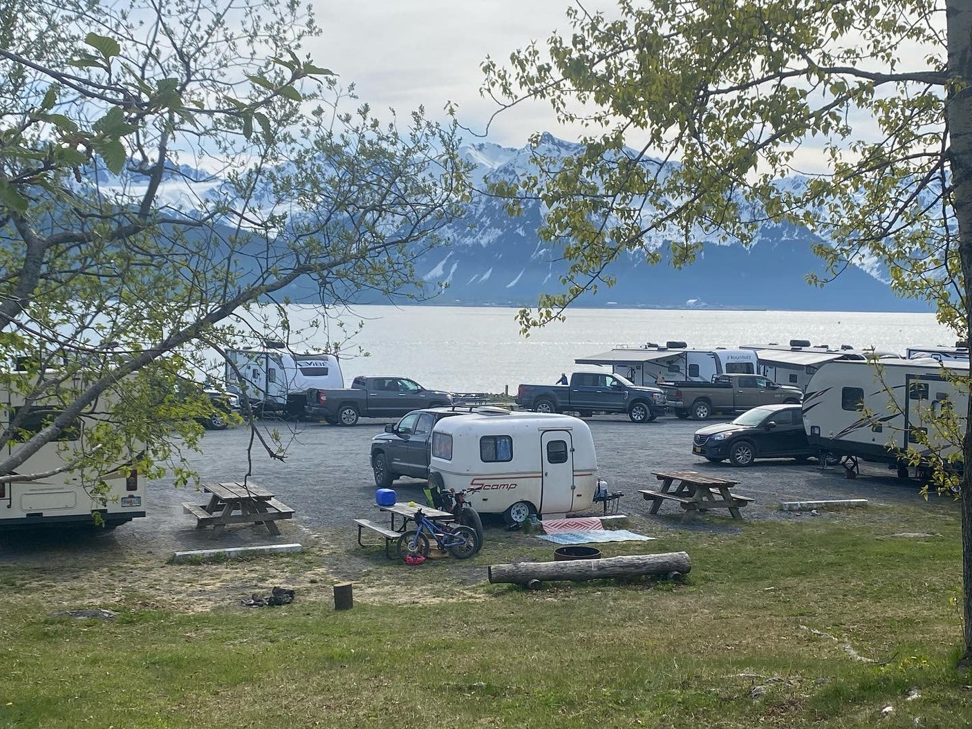 Scenic RV rental campground with various campers, featuring stunning mountain and waterfront views. Ideal for outdoor adventures.