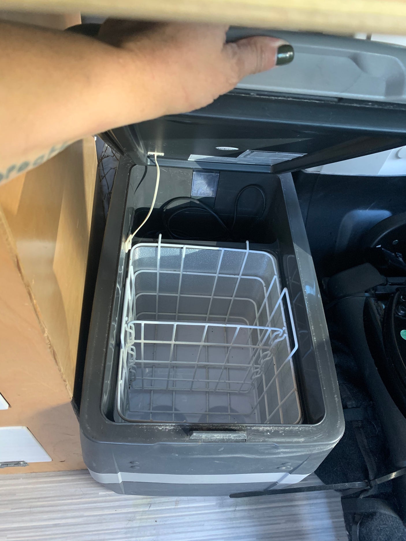 An open portable electric fridge inside an RV rental, showing its wire basket for organized food storage.