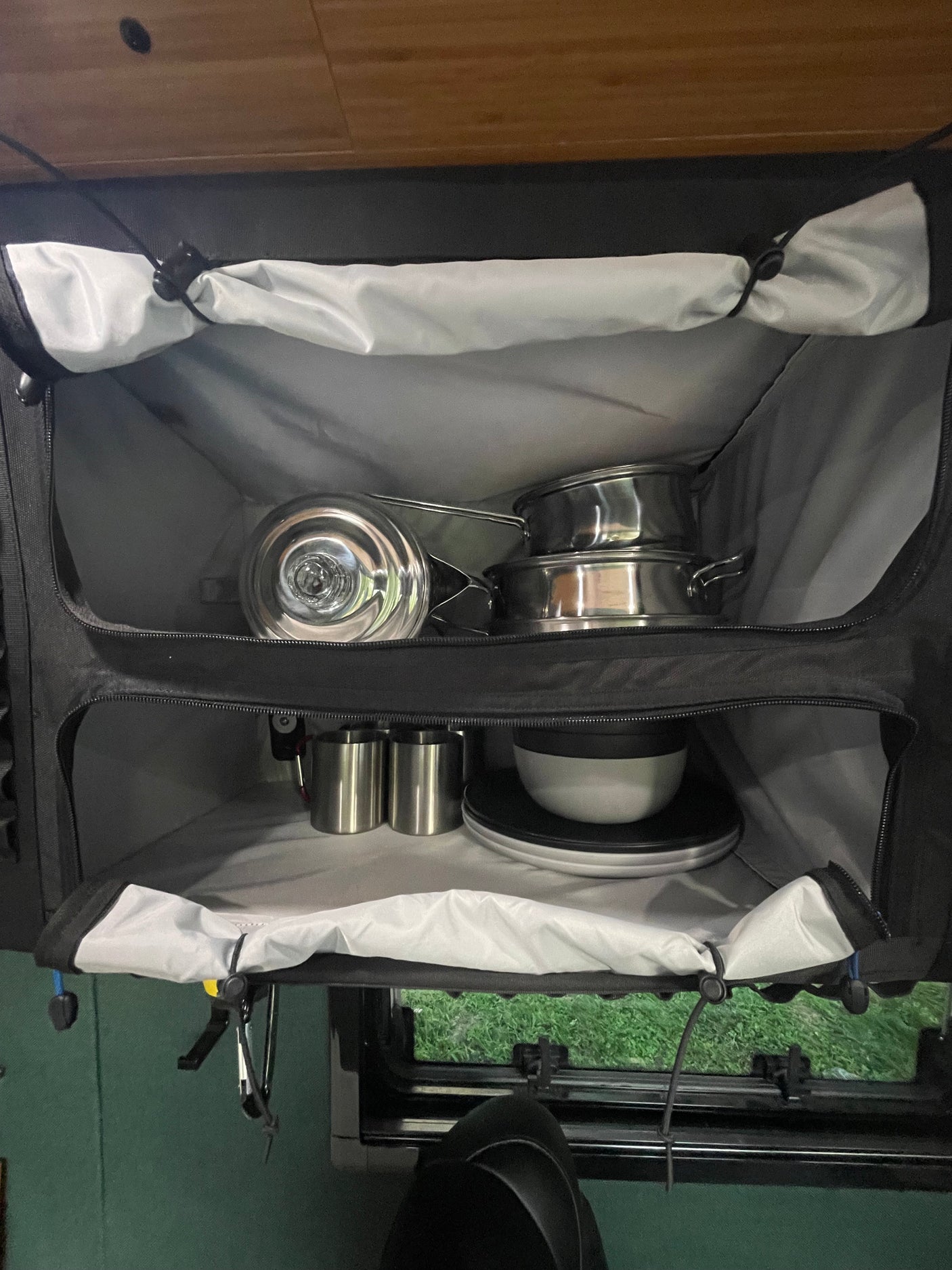 Convenient kitchen setup in an RV rental: metal pots, pans, and tableware neatly stored in a multi-compartment organizer.