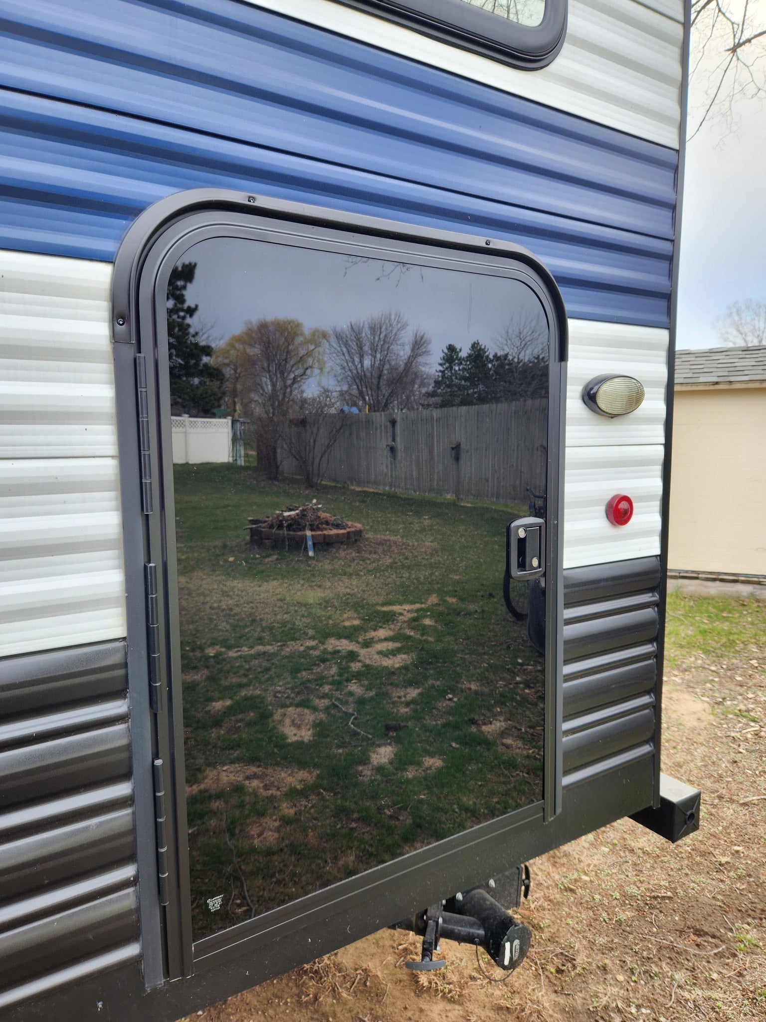 parked on gravel with pine trees.|Explore in this stylish Wolf Pup RV rental! A compact travel trailer with white/blue stripes