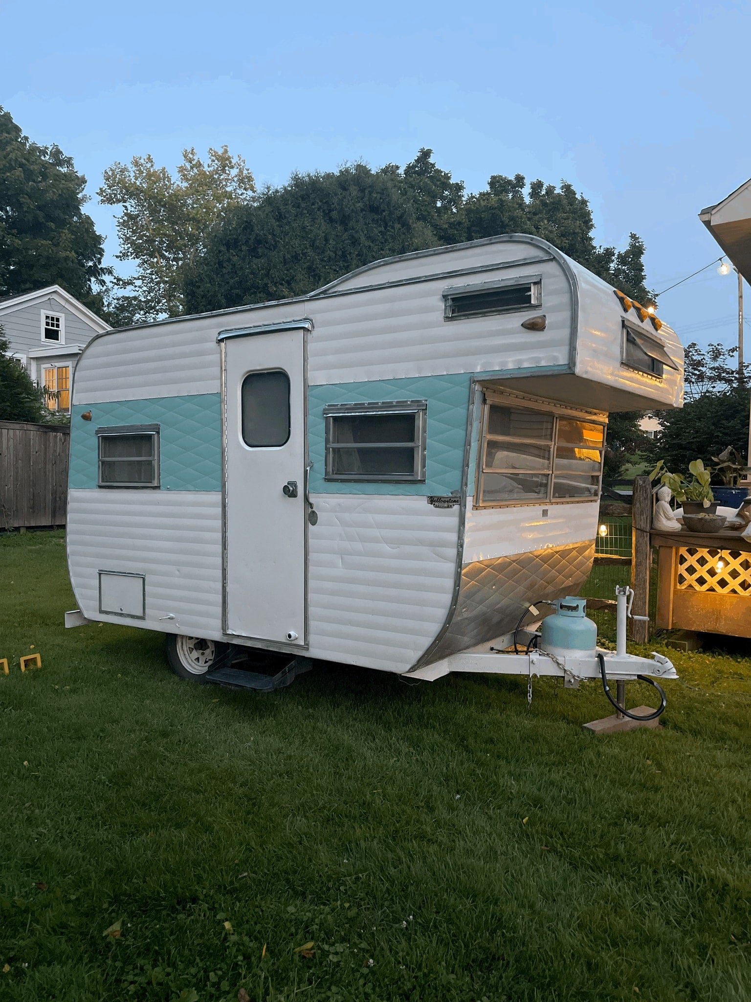 A vintage teal and white travel trailer on grass