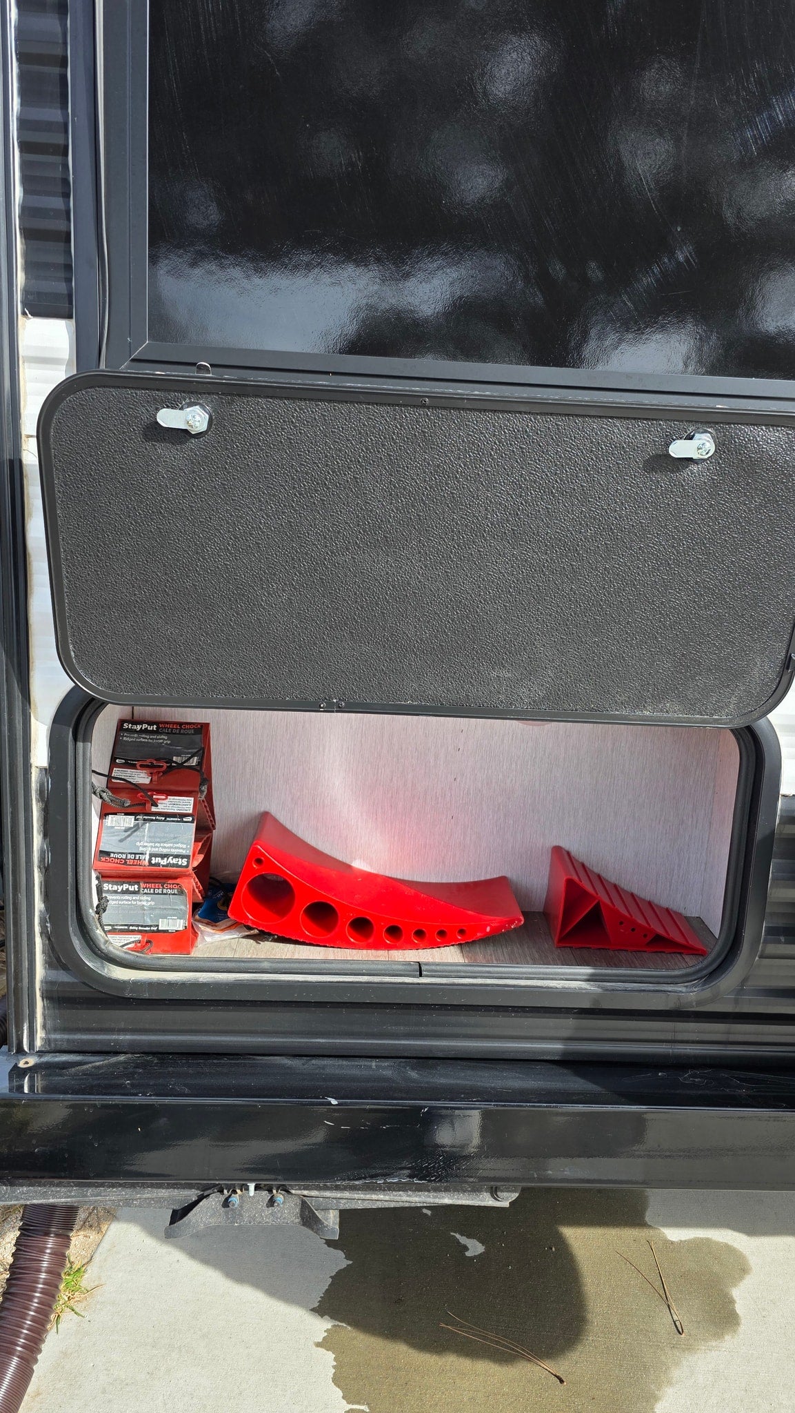 Open RV storage for your rv rental, revealing red wheel chocks & leveling ramps for stability. — photo 11