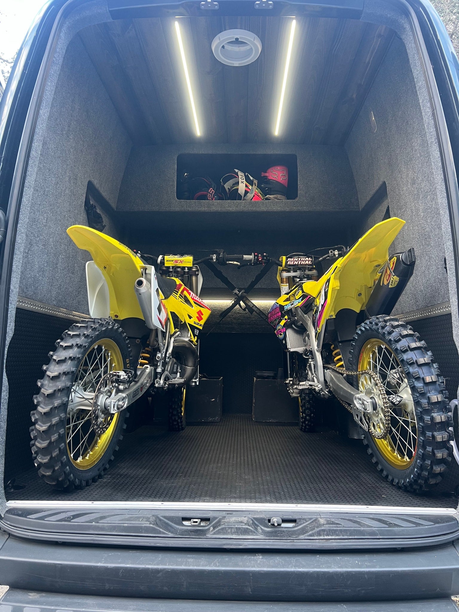 Two yellow dirt bikes stored in a customized moto van, ideal for rv rental adventures.