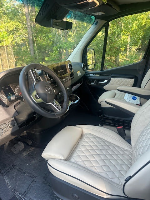 Step into this luxurious rv rental: a modern Mercedes-Benz driver's cabin featuring spacious light quilted leather seats and sleek dashboard.