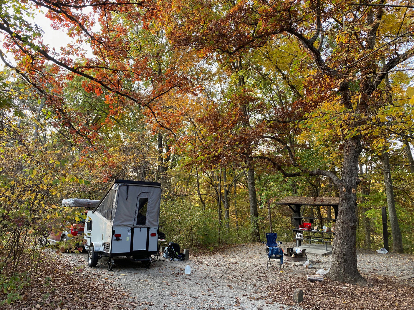 Enjoying an RV rental at a scenic autumn campsite. A pop-up camper, vehicle, and picnic area are nestled among colorful fall trees.