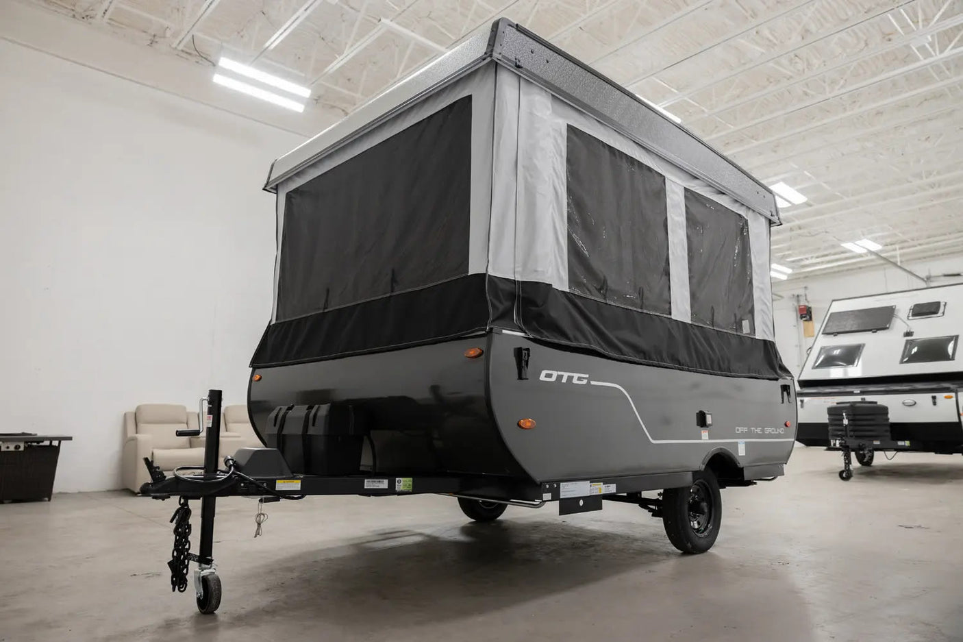 This dark gray and black pop-up travel trailer, a versatile RV rental, is set up and ready for camping adventures.