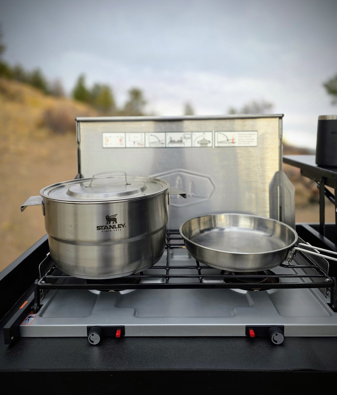 RV rental outdoor cooking: Stanley pot and pan on a portable two-burner stove, set up for meals amidst nature.