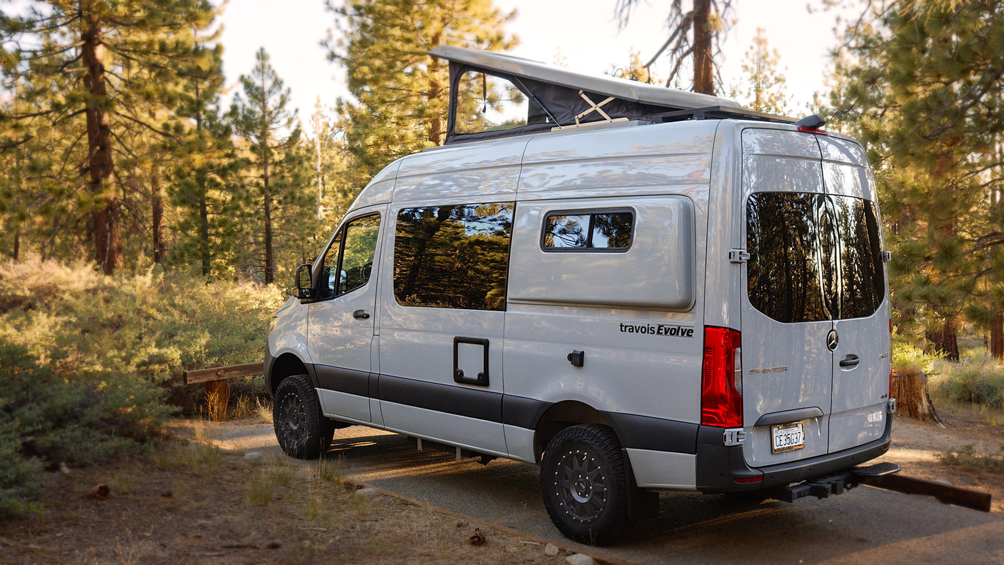 Explore nature with this pop-top Mercedes Sprinter rv rental camper van, parked in a sunlit forest, perfect for your next camping adventure.