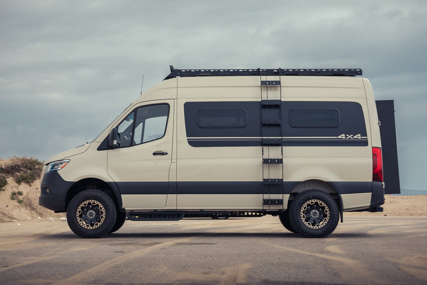 driving on a highway with a roof rack and large rear storage box.|Discover adventure! This rv rental camper van's open rear doors reveal a cozy