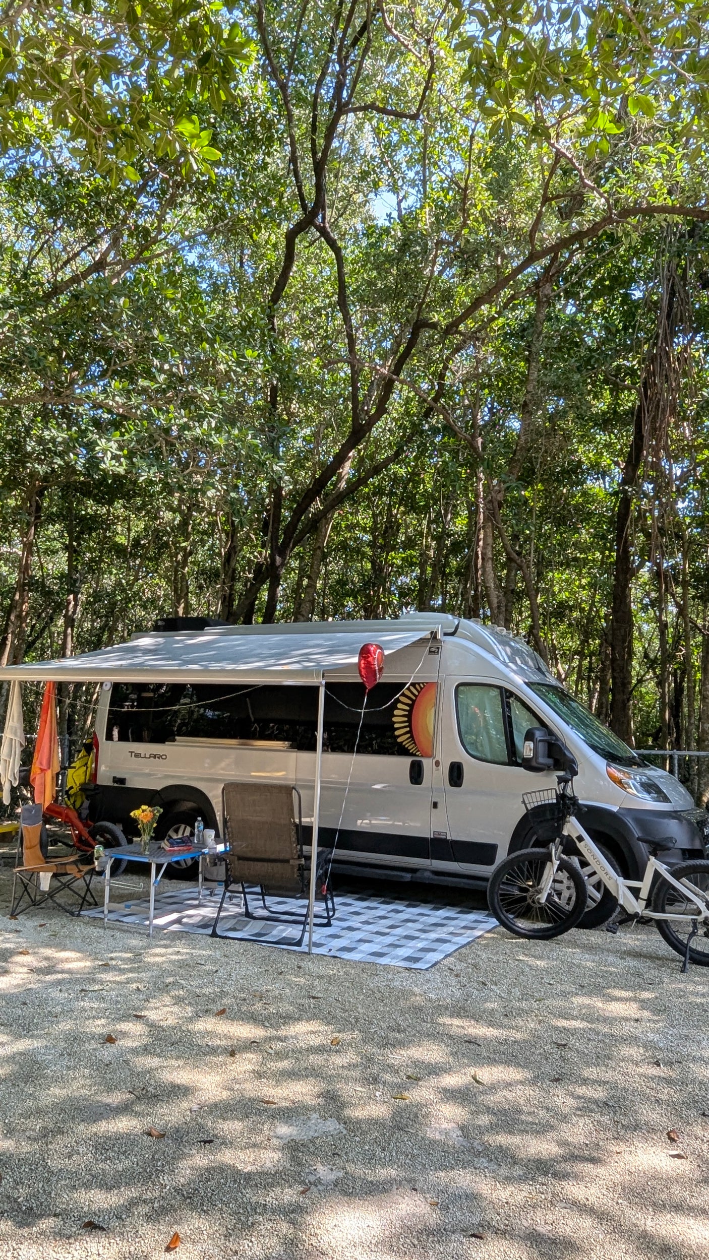 Shaded RV rental campsite setup with an extended awning, outdoor seating, and bicycles for comfortable outdoor living.