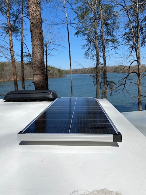 RV rental with rooftop solar panel, perfect for off-grid adventures by a beautiful lake.