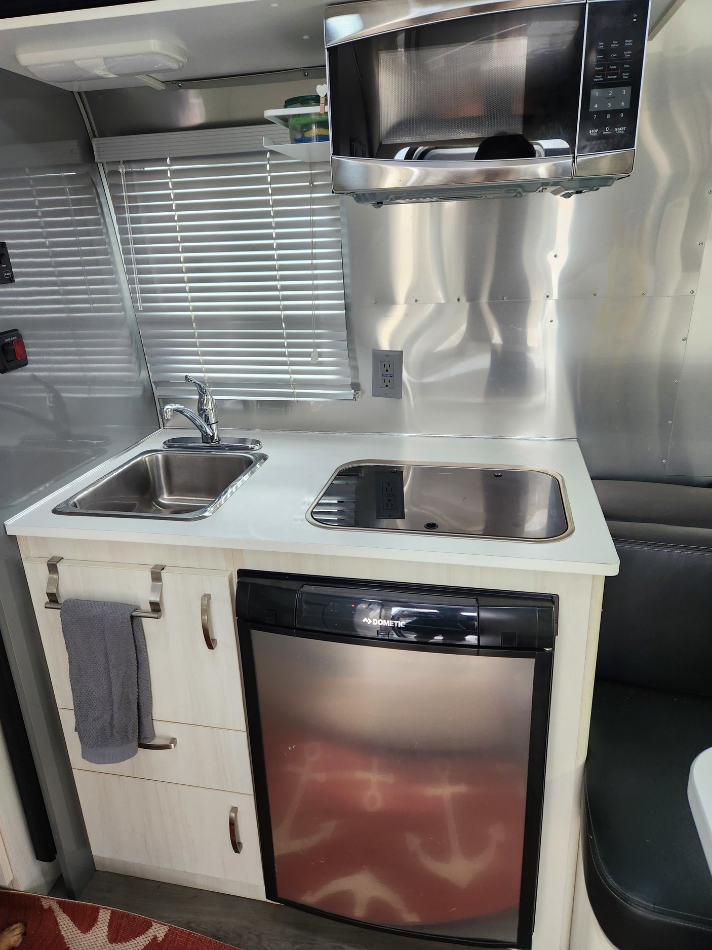 This RV rental kitchenette features a microwave, sink, and Dometic refrigerator, ideal for your next trip.