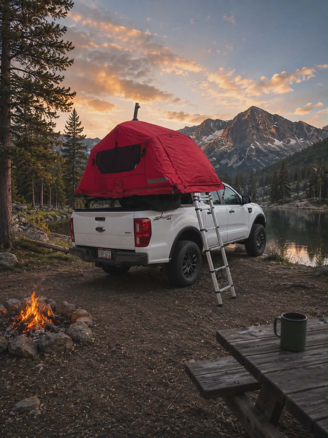 and majestic mountains by a lake. Perfect rv rental setup.|RV rental pickup truck with a roof-top tent overlooks a scenic mountain lake and snowy peaks. Ideal for outdoor adventures.|Adventure awaits with this RV rental alternative: a white truck featuring a red rooftop tent