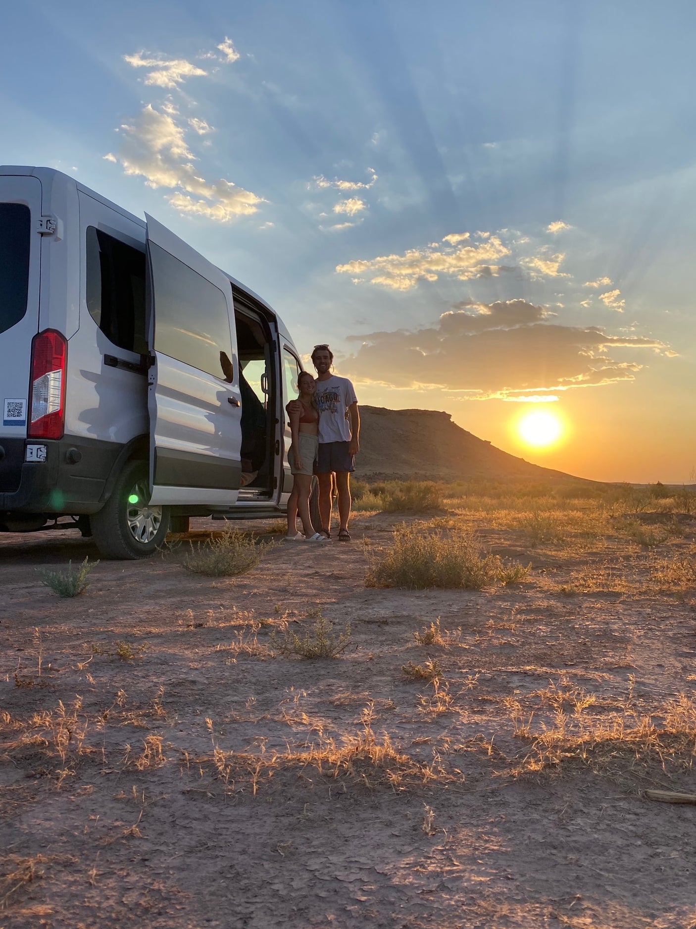 Couple enjoying a stunning desert sunset with their RV rental camper van.