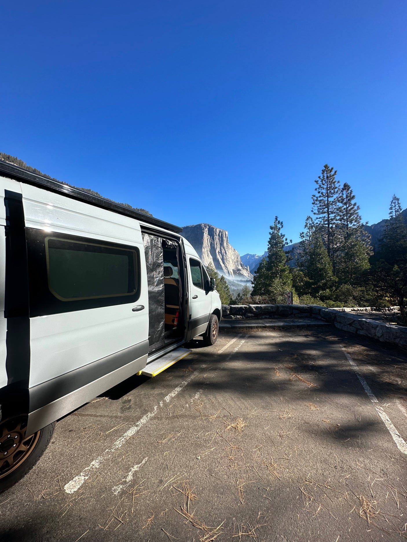 Modern RV rental camper van at Yosemite National Park, open to reveal El Capitan and a misty valley. Ideal for adventure.
