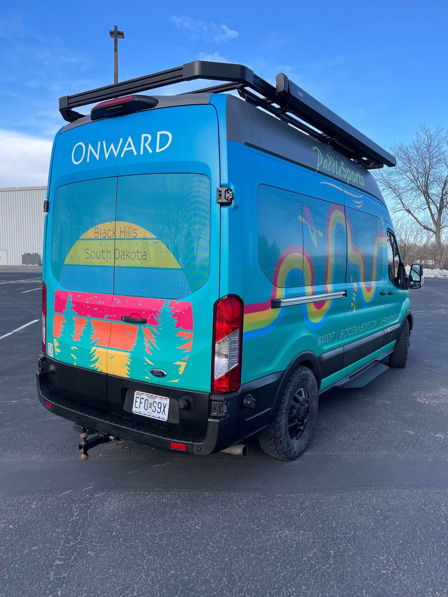 This vibrant Ford Transit rv rental, wrapped with "ONWARD" and "PaddleSports" graphics, is ready for SD adventures.