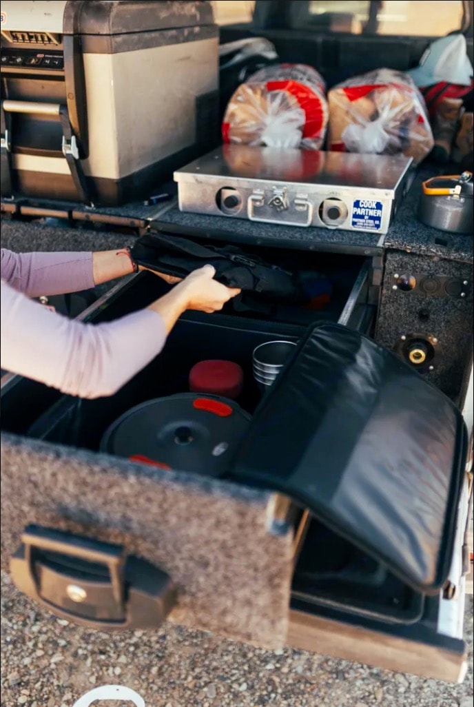 and organized cooking gear in pull-out drawers.|Experience adventure! Woman by campfire at dusk