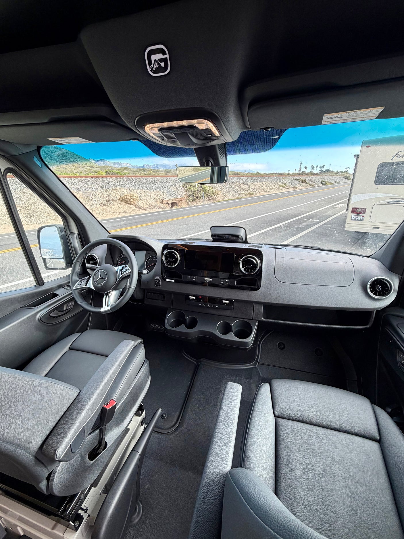 Inside an rv rental: View from the passenger seat shows the modern Mercedes-Benz cockpit, dashboard, and road ahead.