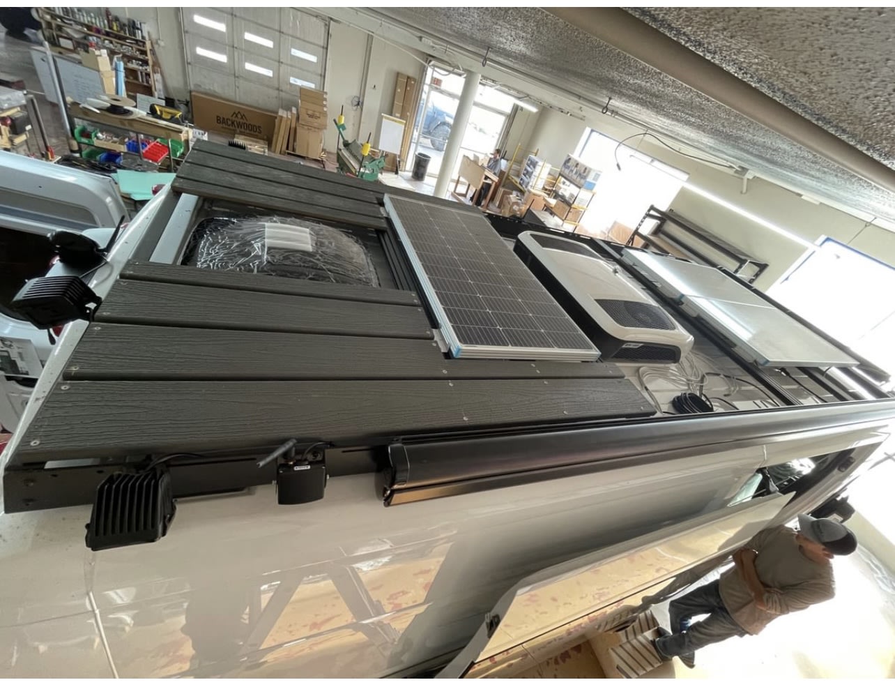 and discreet bathroom. Ready for adventure.|White RV rental rear view: equipped with a sturdy black ladder and a secure storage box for extra cargo.|Step inside this custom RV rental. Features include a compact kitchen