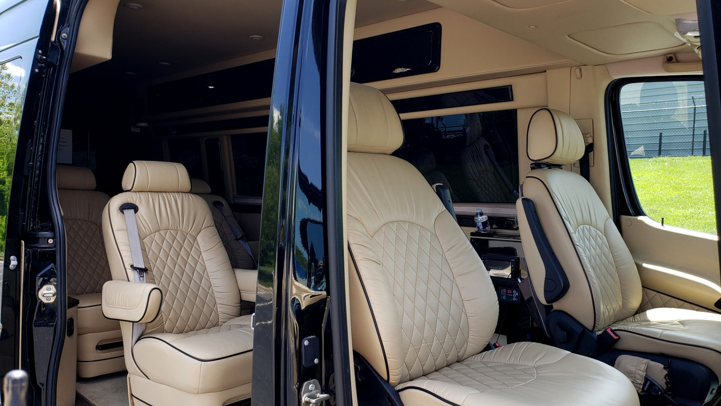 Plush RV rental interior featuring diamond-stitched tan leather seats, armrests, and spacious design.