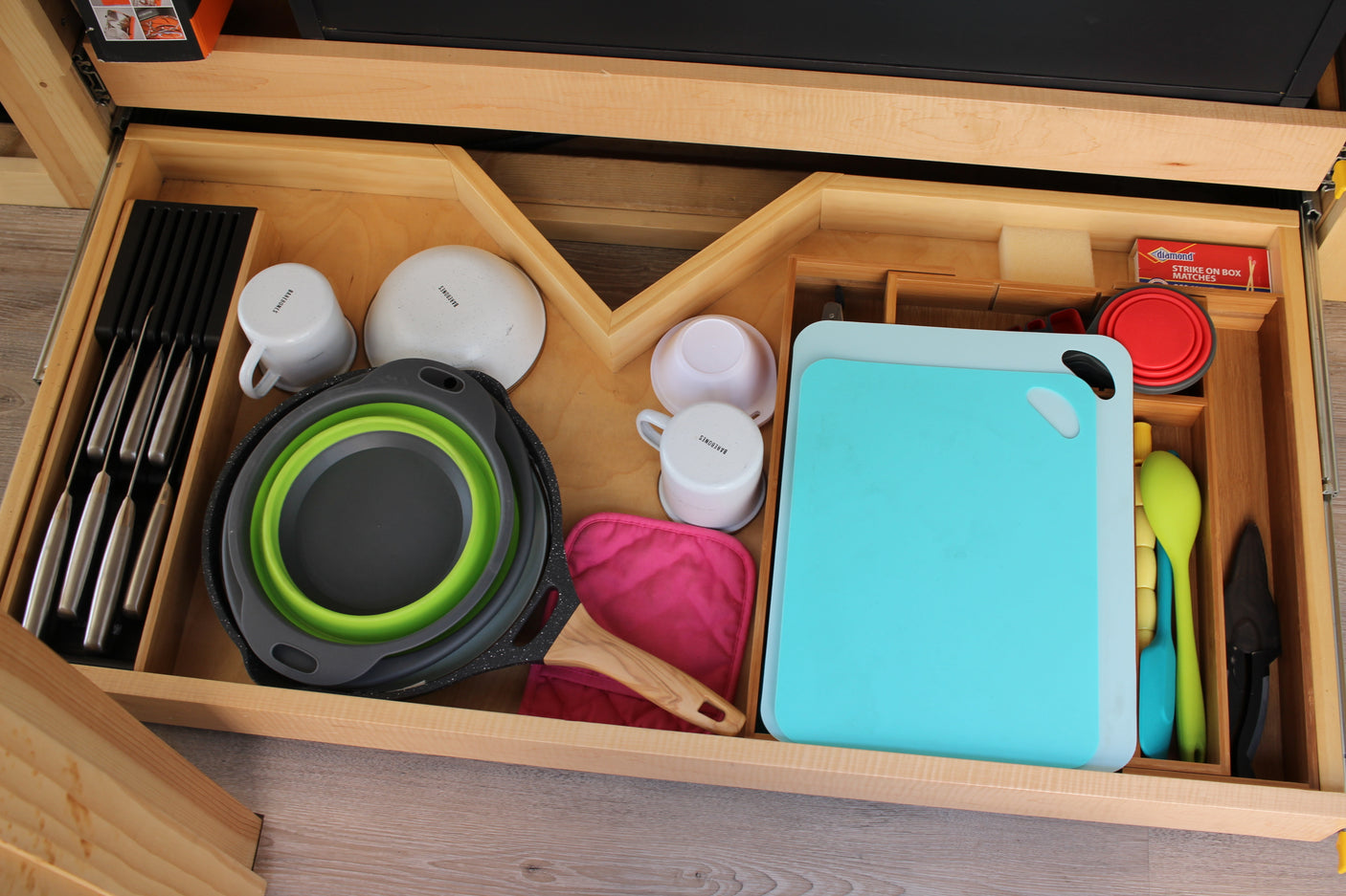 Neatly organized RV rental kitchen drawer. Includes knives, mugs, bowls, cutting boards, collapsible cookware, and spatulas.