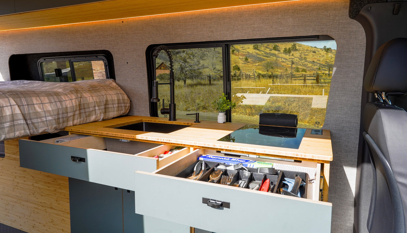 This RV rental interior showcases a modern kitchen, cozy bed, and smart, organized storage solutions for your travels.