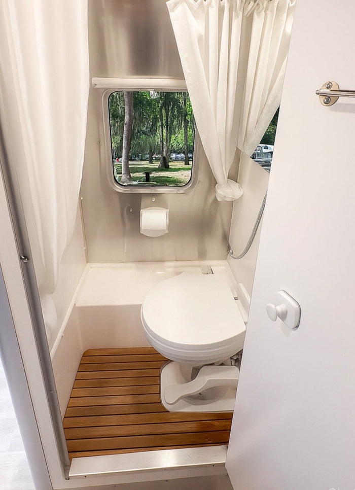 nestled among tall trees in the outdoors.|Modern rv rental interior with compact kitchen