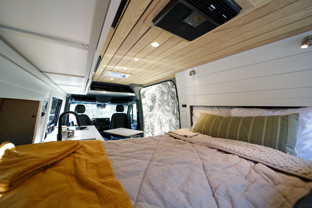 Spacious RV rental interior featuring a comfortable bed, compact kitchen, and versatile living area.