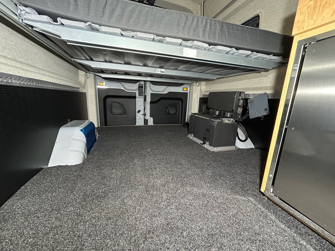 and walls lined with light-colored fabric and mounting tracks.|RV rental camper van interior featuring soft fabric walls — photo 11