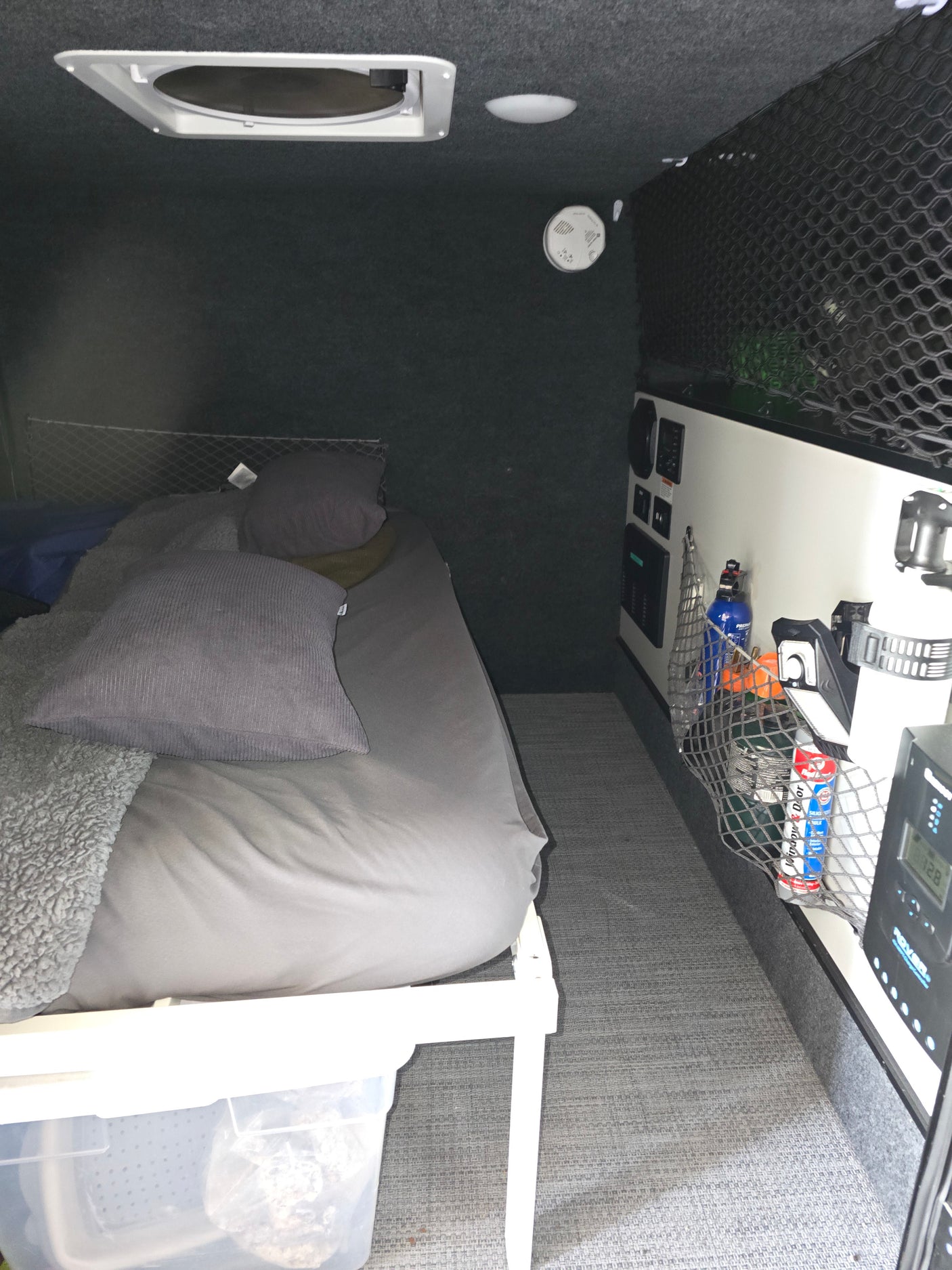Well-appointed RV rental interior featuring a comfy bed, overhead vent, smart storage, and control panel.