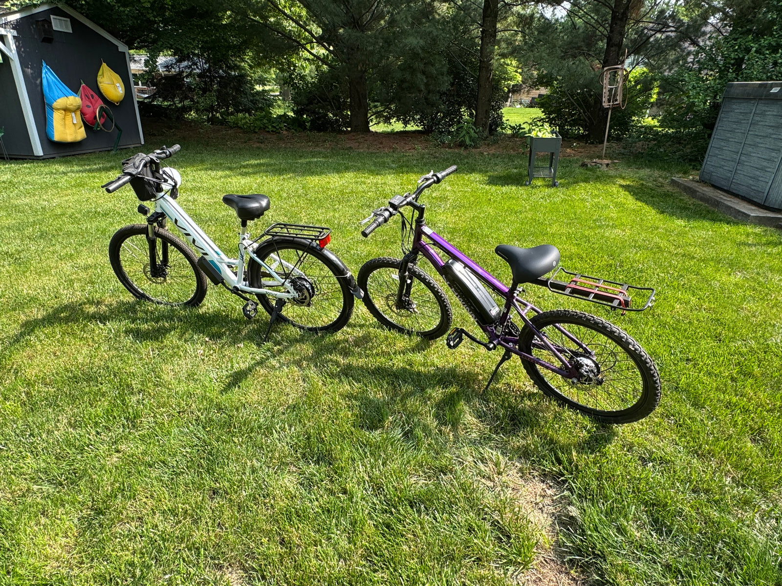 Two electric bikes on a sunny green lawn by a shed, perfect for outdoor fun or an RV rental adventure.