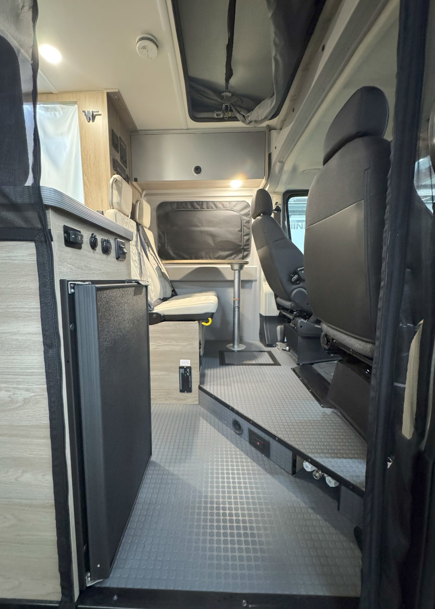 This RV rental offers a well-appointed interior: dinette, fridge, controls, and swiveling front seats for mobile living.