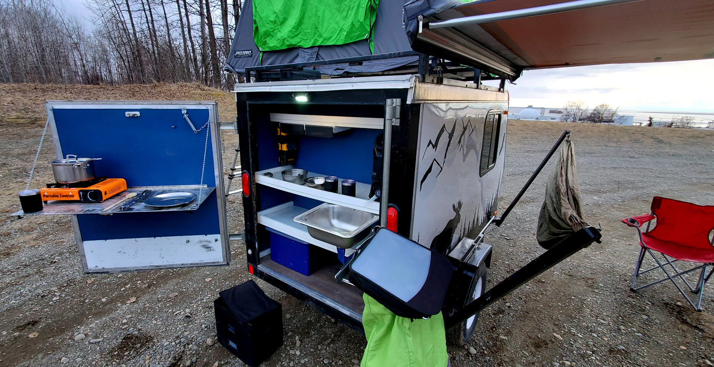 Explore with this rv rental overland trailer, featuring a rooftop tent and a compact, functional outdoor kitchen.