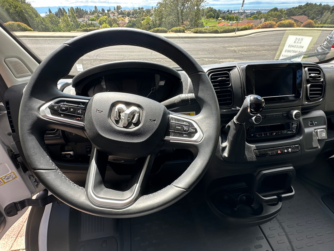 Ram van interior showing the steering wheel, dashboard, and a view of the road ahead, suggesting an RV rental.