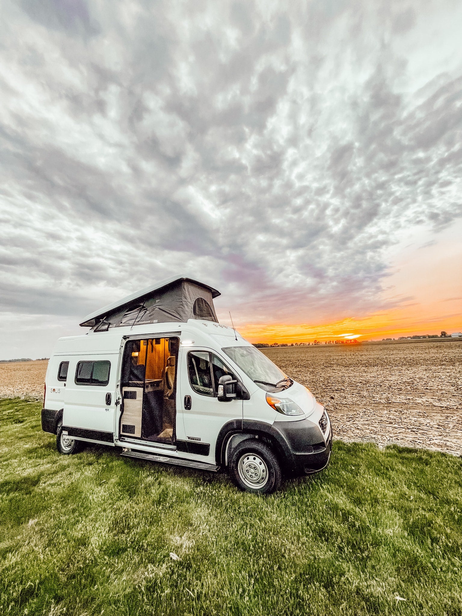 beside a field at sunset. Ideal for an RV rental journey!|RV rental interior: cozy seating