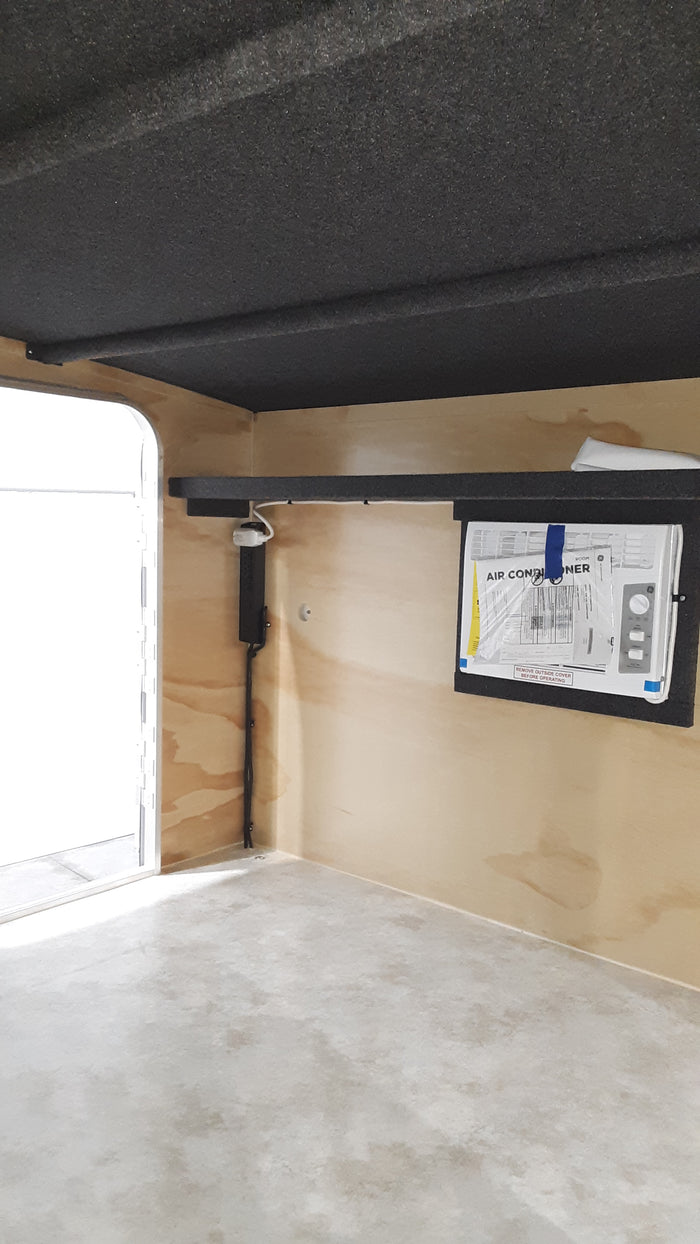 RV rental interior showing wall-mounted air conditioner, dark acoustic lining, and wood paneling with water stains.