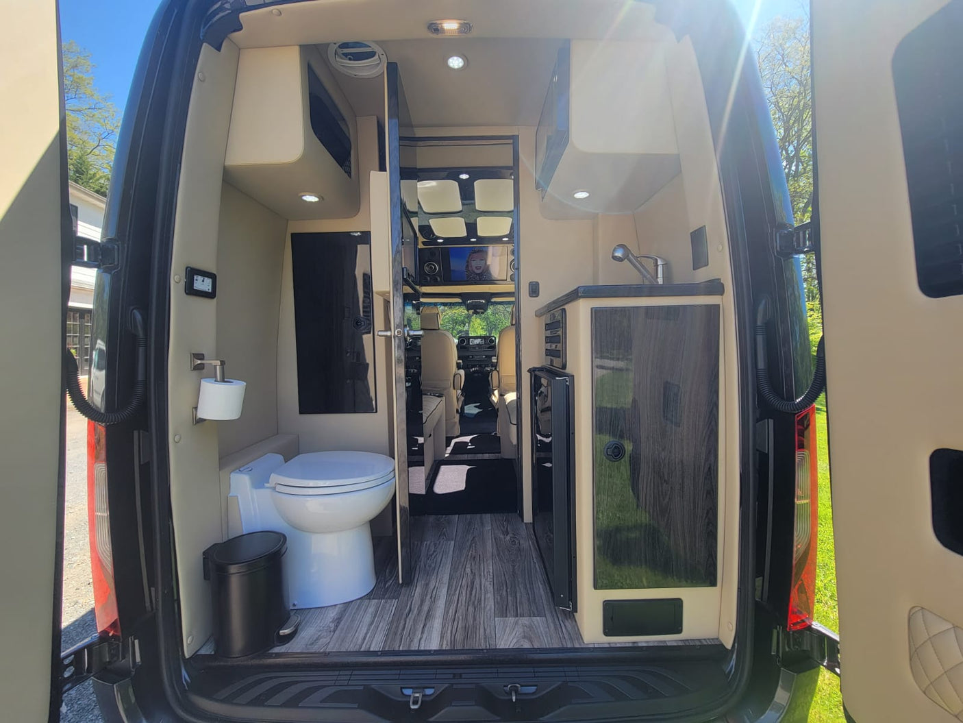 featuring cream leather captain's chairs and bench seating.|Clean rv rental interior from rear: features a modern toilet