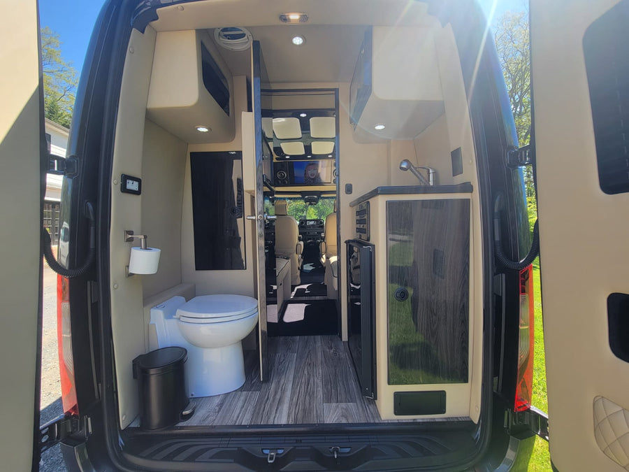featuring cream leather captain's chairs and bench seating.|Clean rv rental interior from rear: features a modern toilet