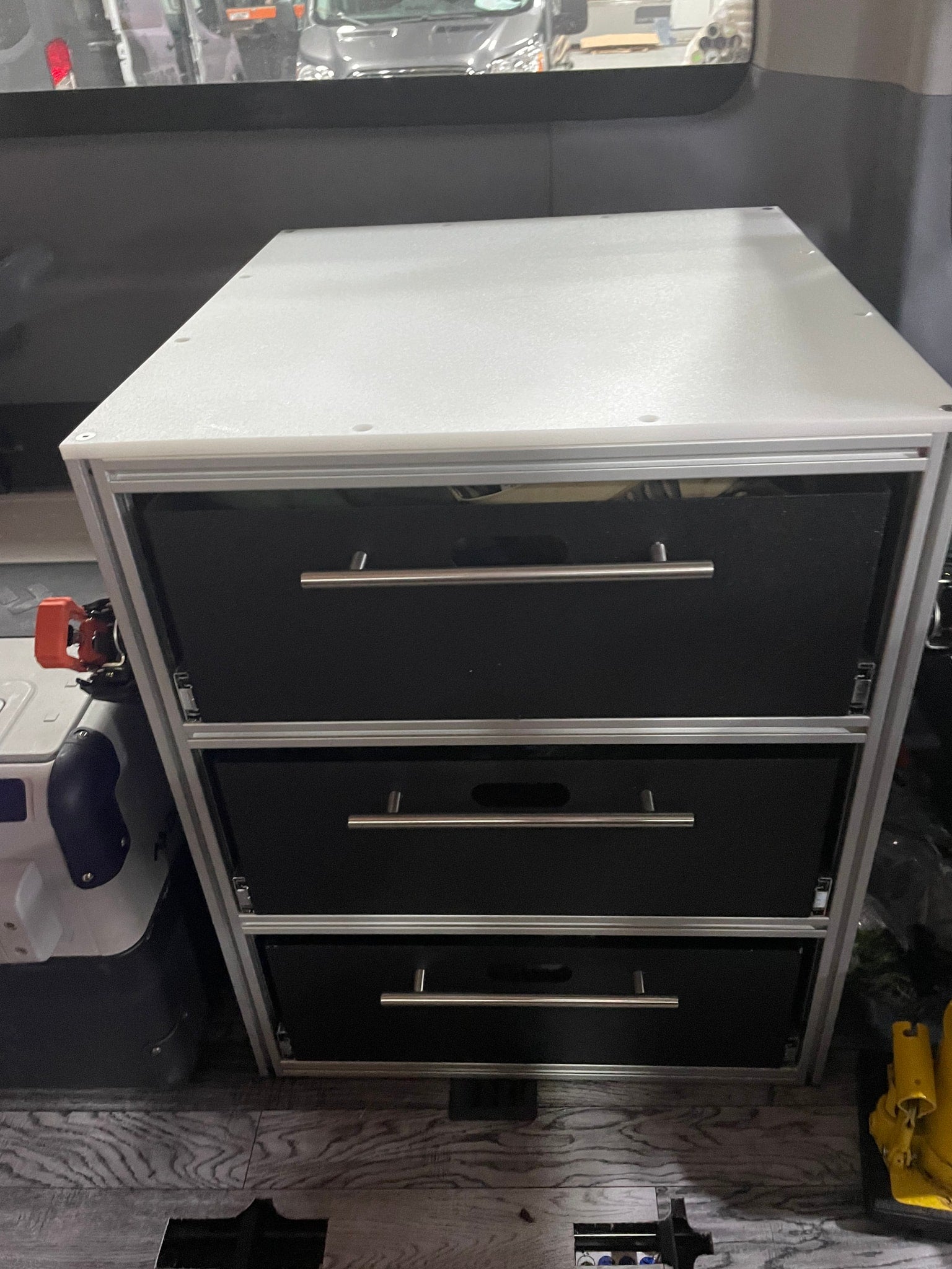 Compact custom drawer storage unit with three black drawers and silver handles, ideal for an RV rental interior.