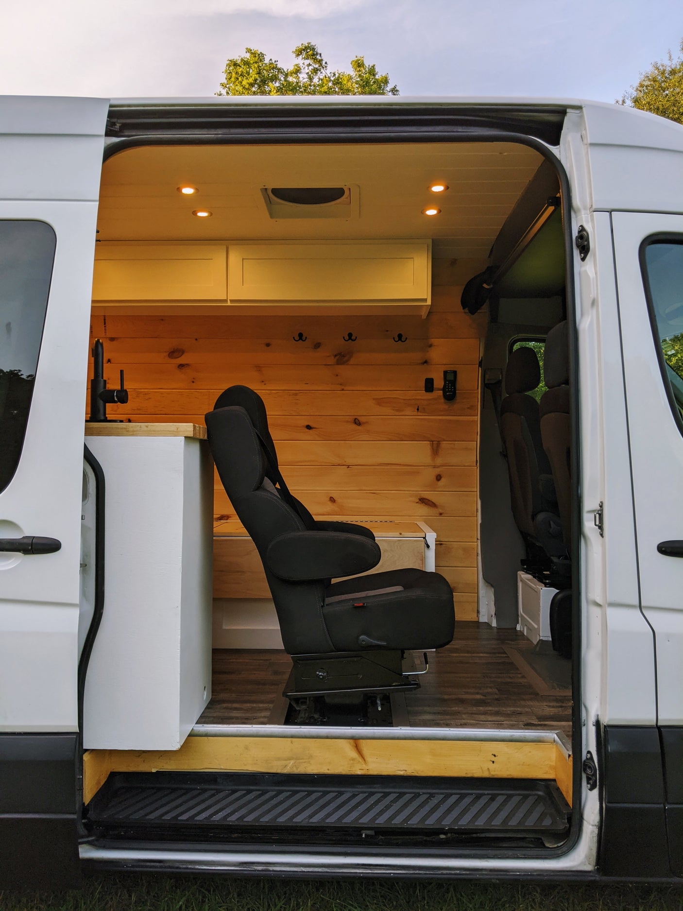 Spacious RV rental: modern camper van interior with wood paneling, a swivel seat, and built-in amenities for travel.