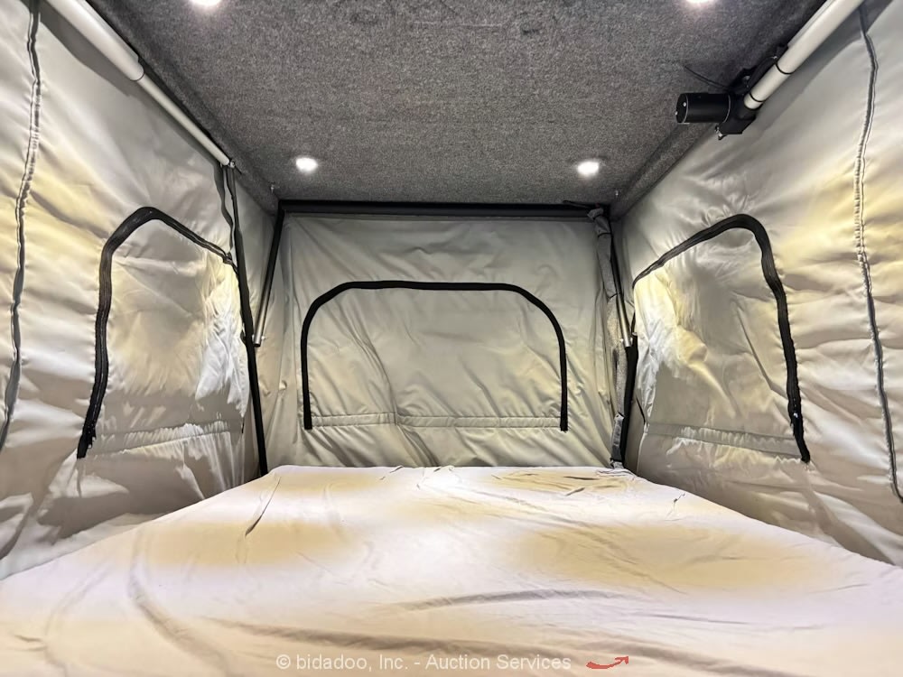 RV rental: Inside a cozy pop-top camper's sleeping area with a bed, fabric walls, ceiling lights, and ventilation.
