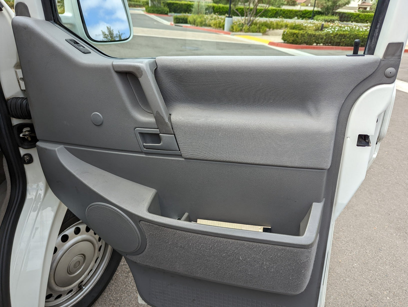Inside an rv rental's door: gray panel, handle, speaker, and storage with notes.