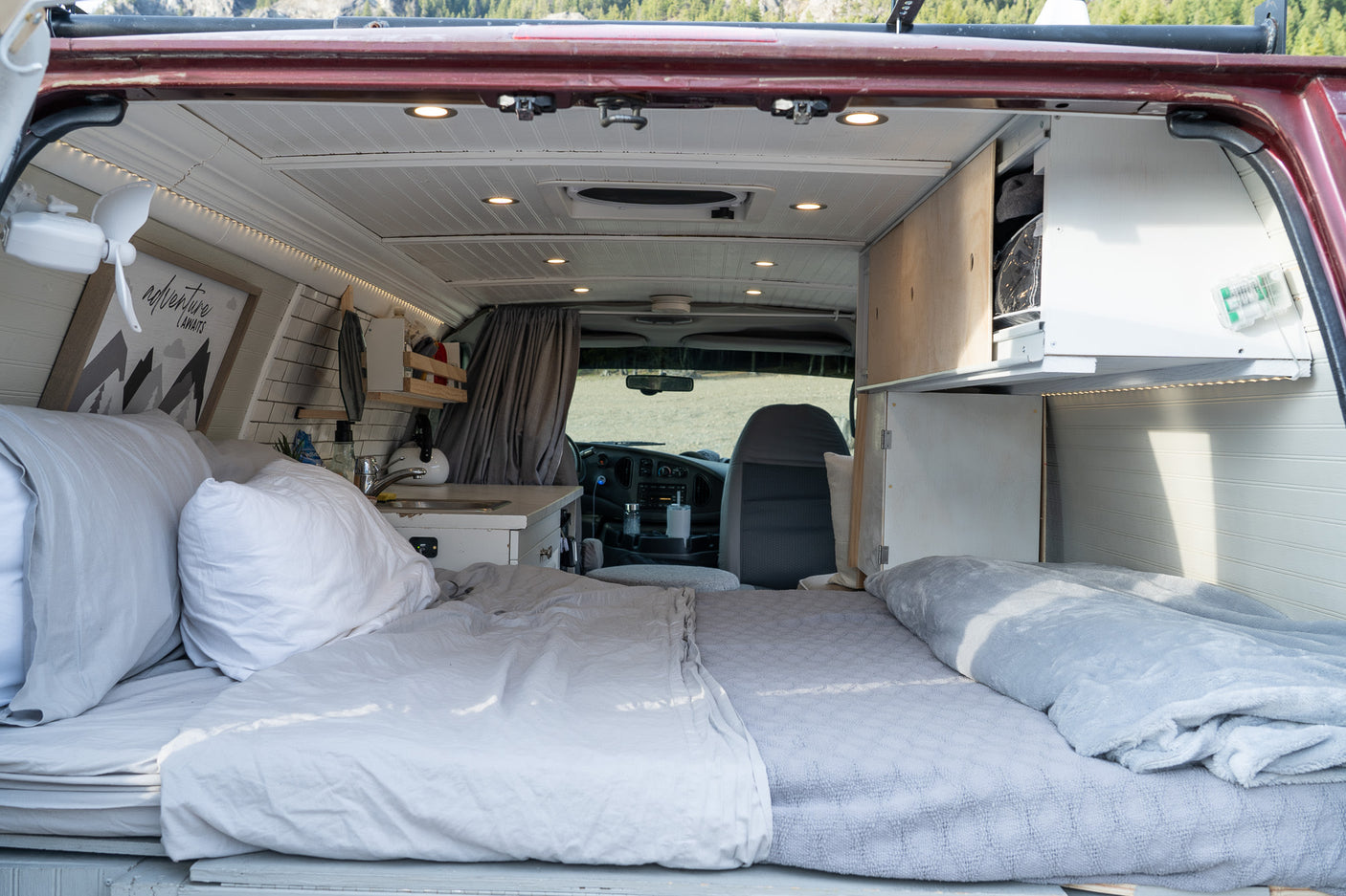 Cozy camper van interior, perfect for an RV rental adventure. Features a comfortable bed, mini-kitchen, and clever storage.